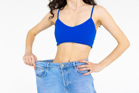 Diet concept. diet results. Before and after, fat and slim, losing weight. caucasian girl. Slimming young woman wearing big pants on lightの写真素材