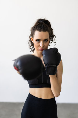 Young and attractive woman in boxing gloves standing in the living room