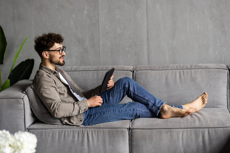 handsome man surfing on tablet on a couchの写真素材