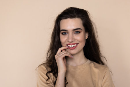 Healthy woman holding hand on belly against beige backgroundの写真素材