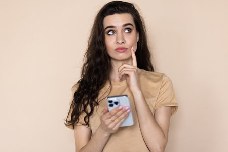 Photo of pretty charming woman typing gadget looking empty space isolated beige color backgroundの写真素材