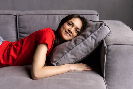 Happy woman lying on couch at home.の写真素材