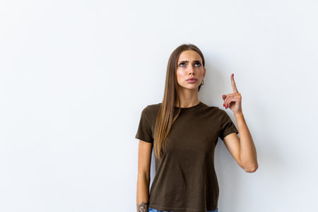 Young beautiful asian woman pointing to copy space, isolated on white backgroundの写真素材