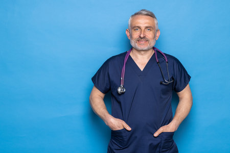 Mature male doctor wearing medical mask on blue backgroundの写真素材