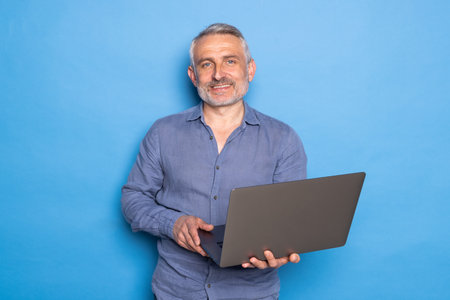 Portrait of positive man worker work on his computer text with his family colleagues wear yellow shirt isolated over blue color backgroundの写真素材