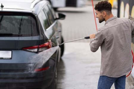 Young man washes a car at a self-service car wash.の写真素材
