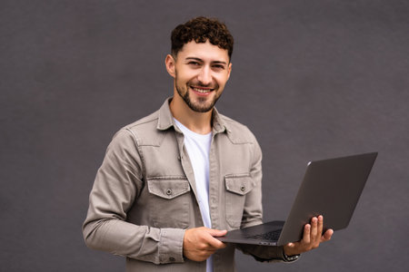 Smiling man in suit and glasses with laptop near office buildingの写真素材