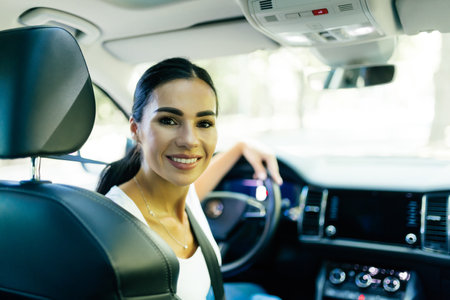 Elegant woman driver looking at backseat, smiling happy, asking passanger fasten seatbelt....