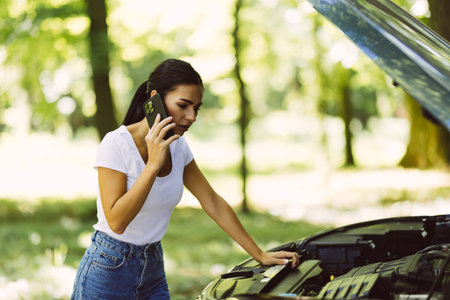 Car breakdown on road. Young desperate woman calling emergency help near broken car on road. Help needed. car service.の写真素材