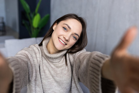 Picture of young smiling woman indoors at home take selfie by camera.の写真素材