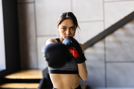 Young and attractive woman in boxing gloves standing in the living room