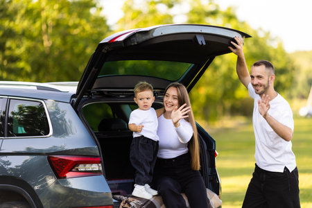 transport, leisure, road trip and people concept - happy family with little girl sitting on trunk of...