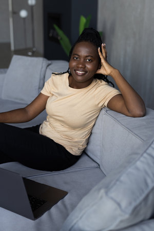 beautiful mixed race woman working working with laptop on couchの写真素材