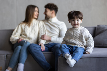 Laughing happy young family posing together in the living room with an adorable young boy with missing front teeth flanked by his attractive smiling parentsの写真素材
