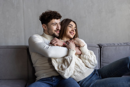 Portrait of a young loving couple resting on a couch together at home and hugging