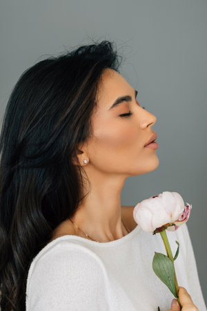 young woman posing with peony flower isolated over white background