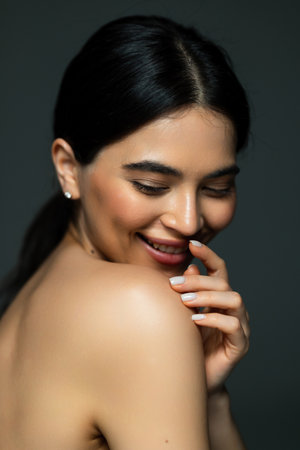 Close up beauty portrait of a laughing beautiful half naked woman applying face cream and looking...