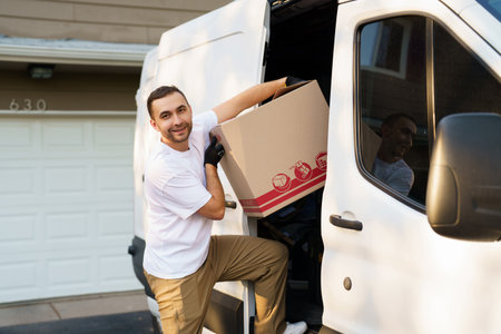 Young delivery men loading cardboard boxes from truckの写真素材
