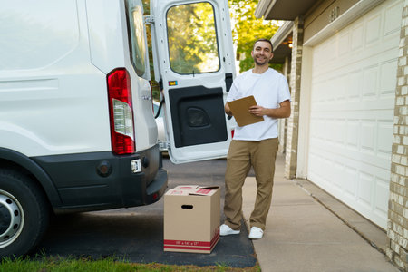 Courier with clipboard checking packages near car outdoorsの写真素材