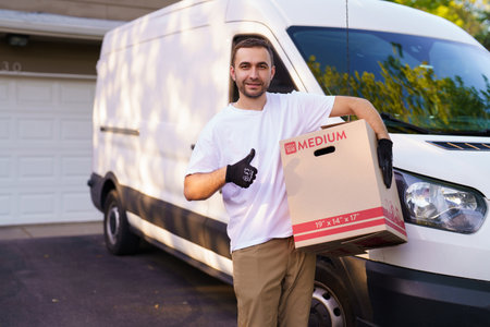 Smiling delivery man holding a paper box