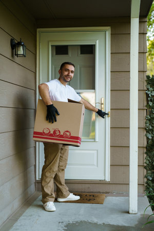 delivery service courier ringing the house doorbell with boxes in hands