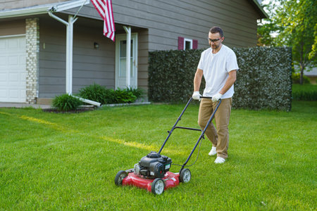 Smiling man standing with lawnmower in garden
