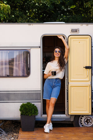 Pretty woman on a road trip with her camper taking a break at sunset