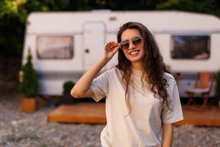 Woman is standing with sunglasses near the camper. Caravan car Vacation. Family vacation travel, holiday trip in motorhome RVの写真素材
