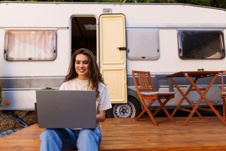 Woman looking at the laptop near the camping. Caravan car Vacation. Family vacation travel, holiday...