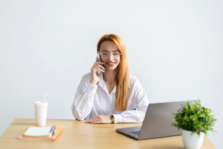 Happy woman using mobile phone and laptops for work. Confident business woman working from home. Home office.の写真素材