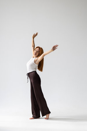 Full length image of Happy woman in shirt having fun and looking at the camera over gray backgroundの写真素材