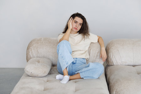 Stressed woman sitting on a couch at homeの写真素材