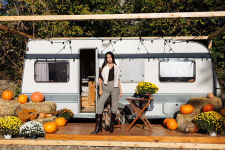 Portrait of young cheerful woman and camper car in the background
