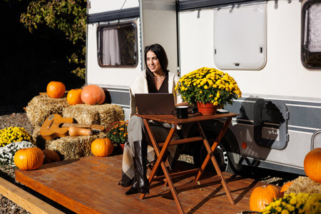 Young woman surfing the net on a computer while camping with a van in nature. Copy space.の写真素材