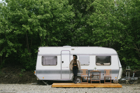 Happy woman standing near camper van in countrysideの写真素材