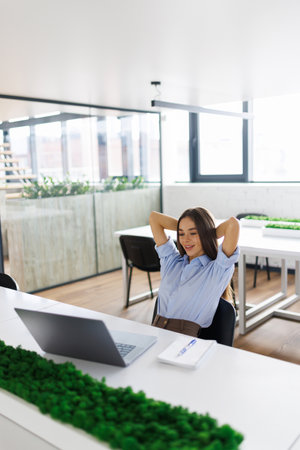 Good Morning. Happy businesswoman working at office and stretching her arms, front view, copyspace, panoramaの写真素材