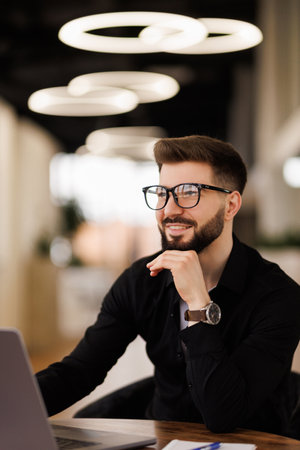 A focused business professional working at a desk in a modern office setting, displaying concentration and dedication to tasks on a computer. Ideal for depicting corporate work environments.の写真素材