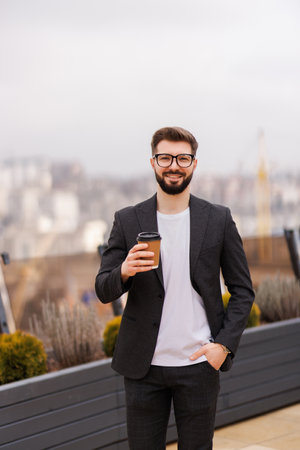 Take a pause. Waist up portrait of smiling businessman while having coffee break on office balconyの写真素材