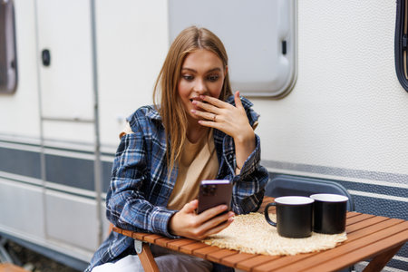 Woman driver enjoy camper parking rv area using phone app to plan next destination of travel. Happy...