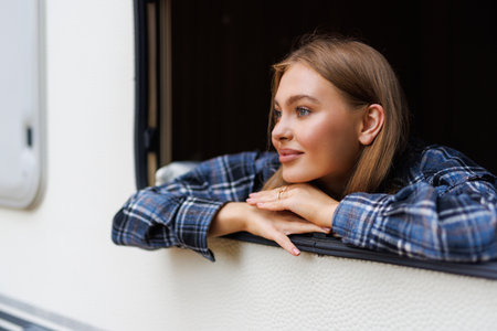 Portrait of young woman smiling at the camper van window. Happy tourist enjoy travel vanlife...