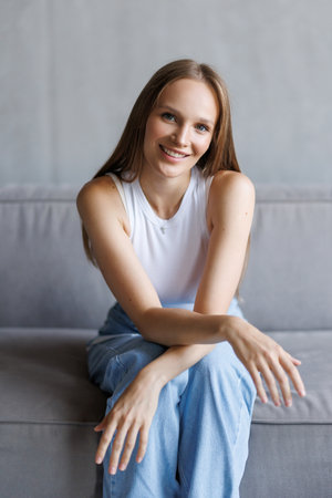 Happy young woman sitting on sofa at home