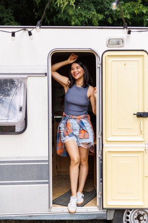 Happy woman sitting with in front of her camper van during a trip