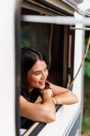 Portrait of young woman smiling at the camper van window. Happy tourist enjoy travel vanlife lifestyle.の写真素材