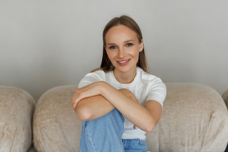 Smiling teenager girl relax sit on sofa at home.