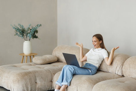 Young woman sit on sofa in living room having operational problems working on laptop, millennial girl feel stressed confused with slow internet connection or computer spamの写真素材