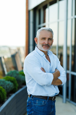 mature man is pondering on terrace of house roof against background of cityscape at sunset. Copy space.の写真素材