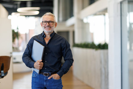 Confident mature businessman professional company executive looking at camera holding tech device,...