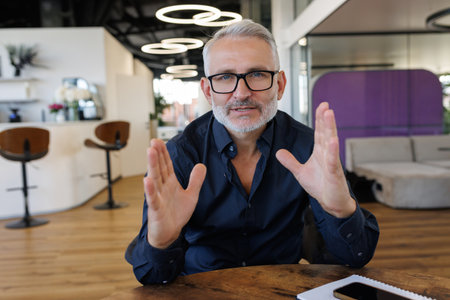 Mature business man gesturing with hands while explaining concepts in office