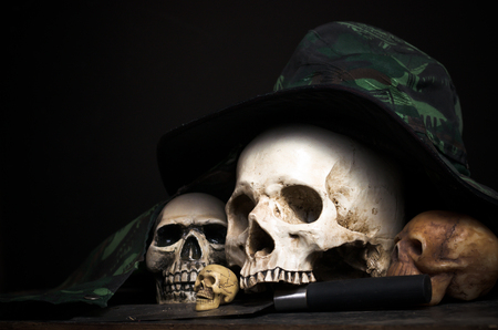 still life of genocide human skulls on the black background with knife and hatの写真素材