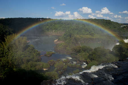 a spectacular rainbow over  the iguazu falls, one of the seven natural wonders of the world, between Argentina and Brazilの写真素材